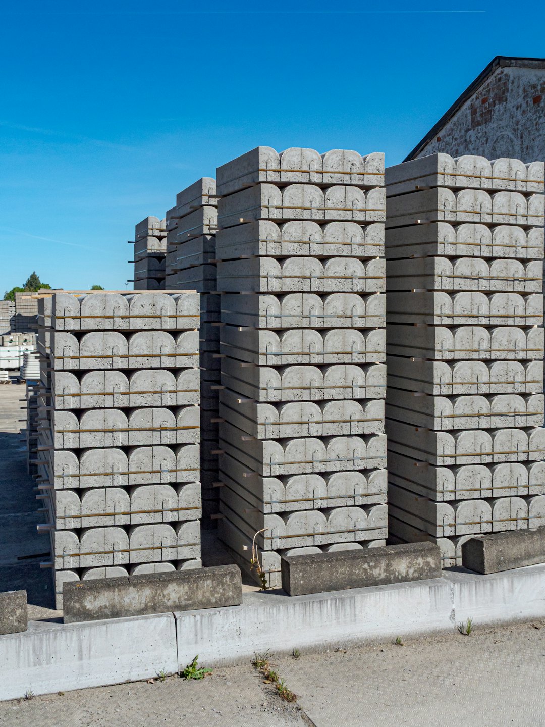 Beton çit direkleri bir sanayi bahçesinde yığılı duruyor.