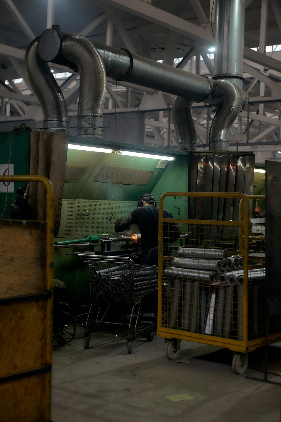 Bir işçi baret takmış, fabrikada metal taşlıyor.